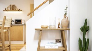A staircase with a wooden handrail, a small table with a vase and books, and a cactus plant. - Beautiful Home in Heart of Truro (Truro)