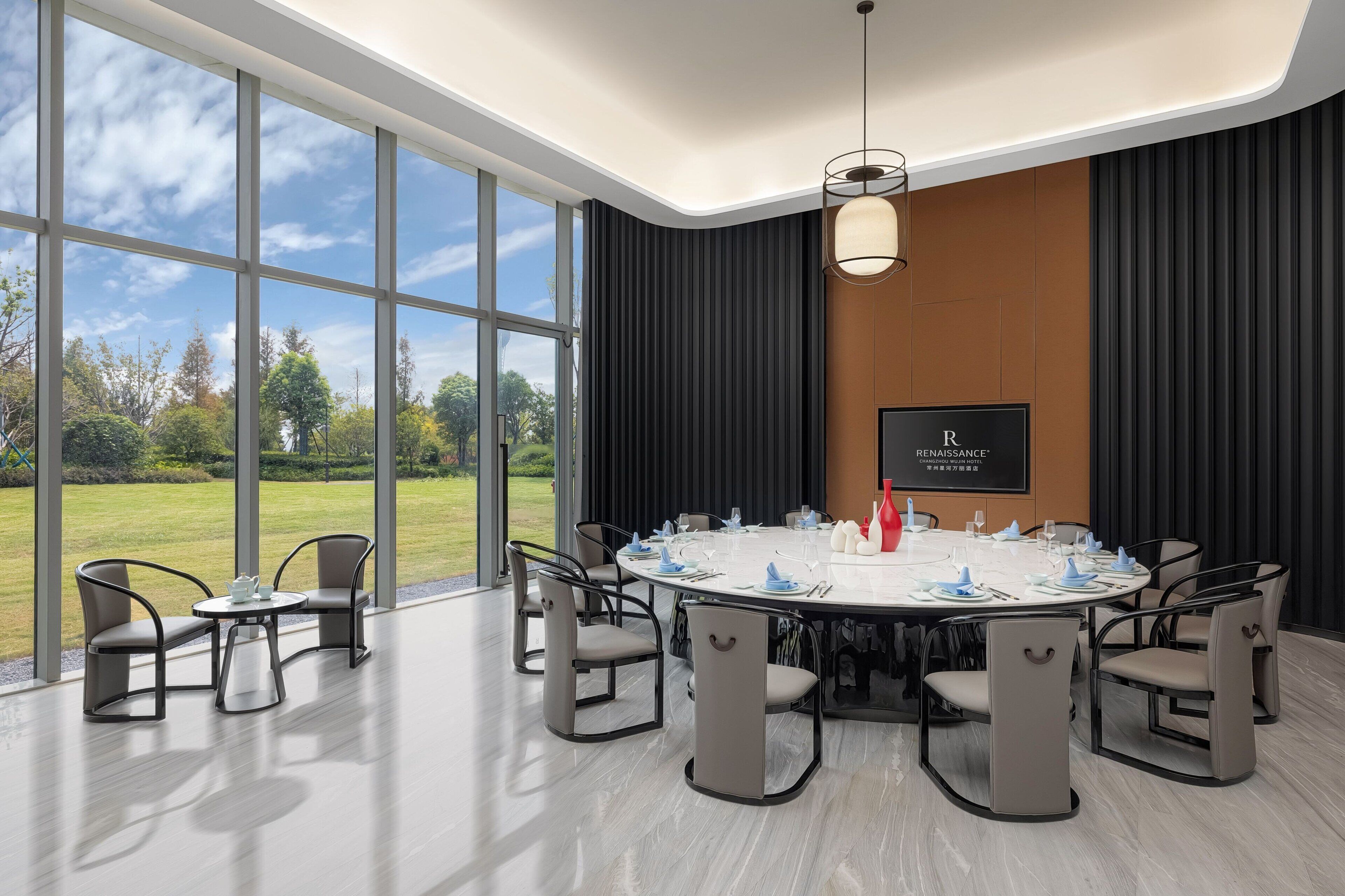 A conference room with a round table, chairs, and a view of the outdoors.
