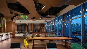 A modern interior with a wooden table, chairs, and a yellow rabbit sculpture. - Renaissance Changzhou Wujin Hotel (Changzhou)