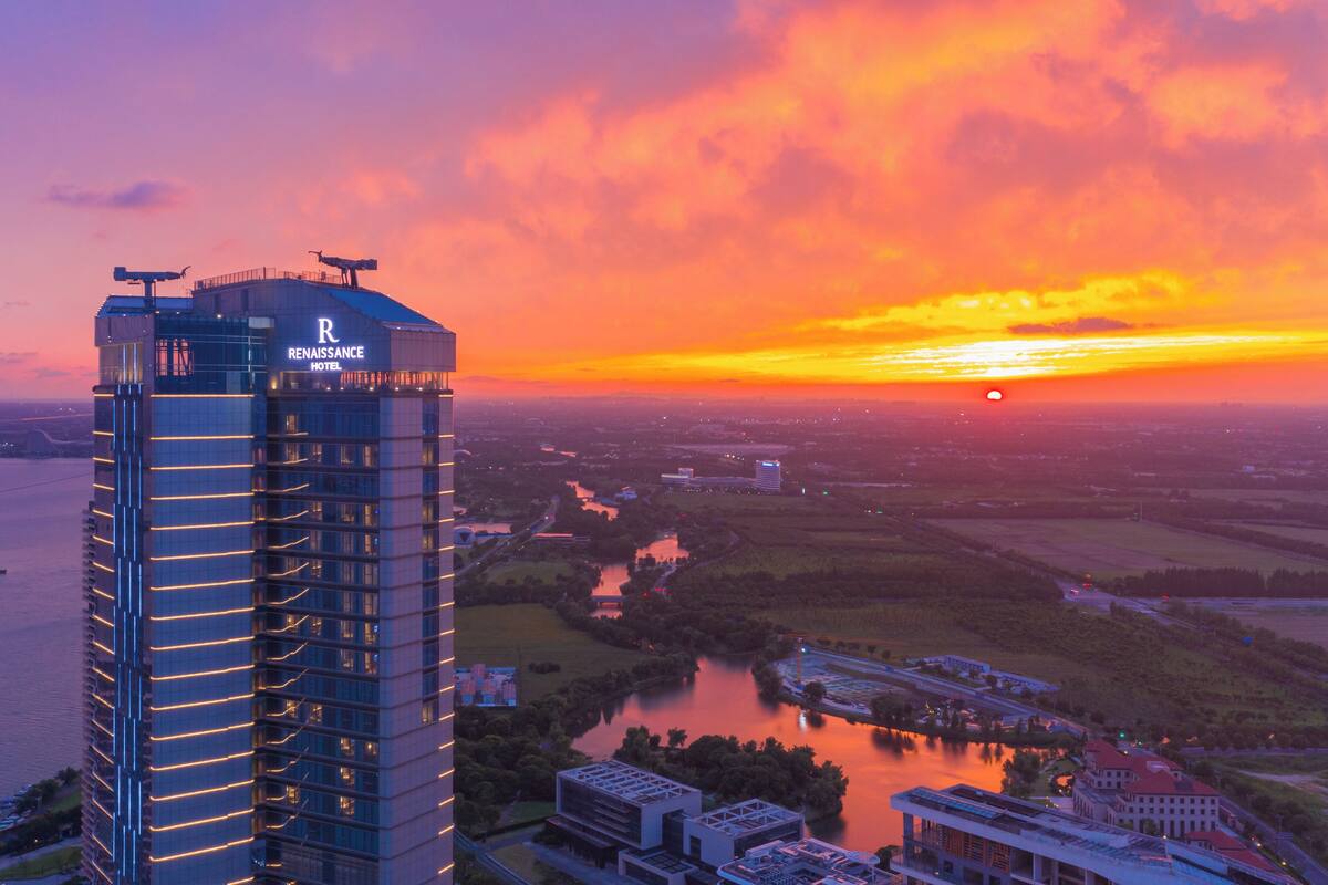 A high-rise hotel with a prominent 'Renaissance Hotel' sign, surrounded by a river and a sunset.