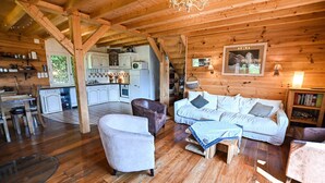 Un intérieur chaleureux de chalet en bois, comprenant un salon, une cuisine et un coin repas.