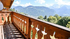 Un balcon en bois offrant une vue sur un paysage montagneux.