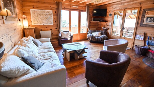 L’intérieur d’un chalet confortable, avec un canapé, des fauteuils, une table et un téléviseur.