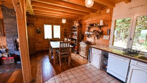 L’intérieur d’un chalet en bois comprend un coin repas, une cuisine et une fenêtre donnant sur un paysage verdoyant.