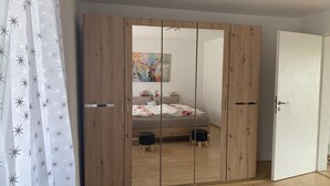 Une chambre avec une armoire en bois, un lit avec une literie à motifs floraux et un tableau accroché au mur.