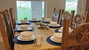 A dining table set with white plates, bowls, and cups, surrounded by wooden chairs with star-shaped backrests. - Spacious 4 br getaway. Riviera Beach / Baffin Bay (Riviera)