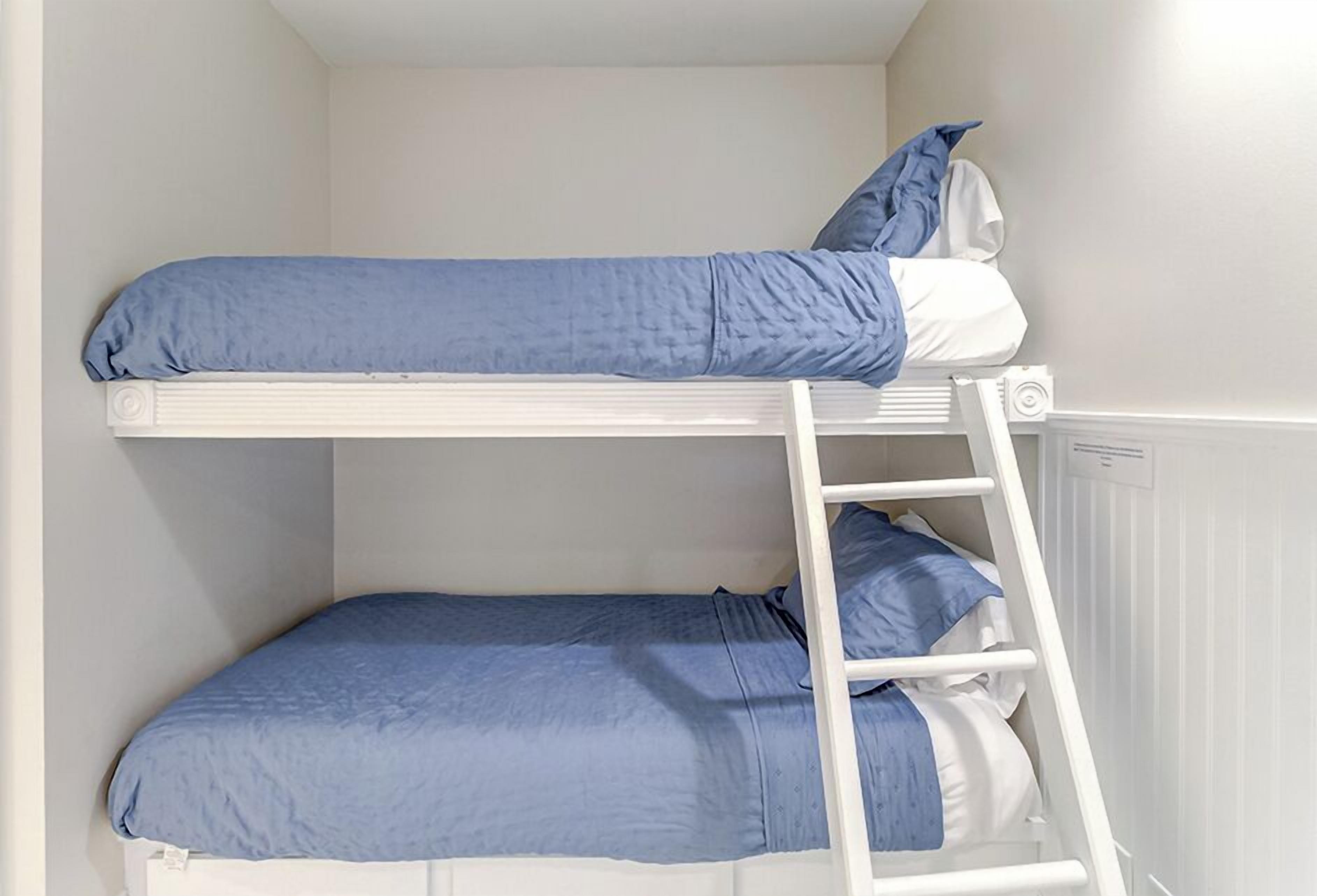 A bunk bed with a ladder, white walls, and a radiator.