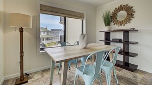 A dining area with a wooden table, light blue chairs, a floor lamp, a large mirror, and a potted plant. - Ocean Views, Balcony, Pool,  STEPS to Beach Restaurants Shops (Wrightsville Beach)