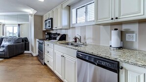Een moderne keuken met witte kasten, een granieten aanrechtblad en roestvrijstalen apparatuur.