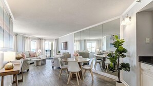 Ein modernes Wohnzimmer mit Essbereich, einem großen Spiegel und einer Topfpflanze.
