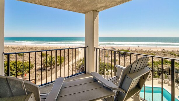 Ein Balkon mit Blick auf den Strand, einen Pool und Sitzgelegenheiten im Freien.