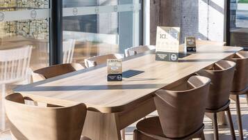 Un comedor moderno con una mesa y sillas de madera, un atril para el menú y una pared de piedra al fondo.