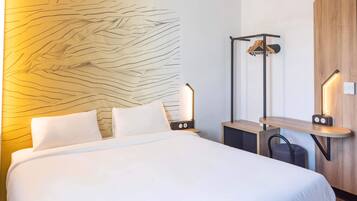 A hotel room with a large bed, bedside tables, a wooden panel wall, and a hanging coat rack.