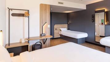 A modern hotel room with a large bed, a desk with a chair, a wardrobe, and a mirror.