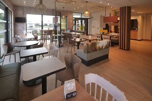 Ein modernes Café mit verschiedenen Sitzbereichen, darunter Tische und Stühle, sowie einer Theke mit einer Produktpräsentation.