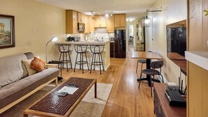 Un espacio habitable compacto con sofá, mesa de centro, zona de cocina y mesa de comedor.