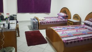 Ein Zimmer mit zwei Holzbetten, einem Schreibtisch, einem Stuhl, einem kleinen Tisch und einem roten Teppich.