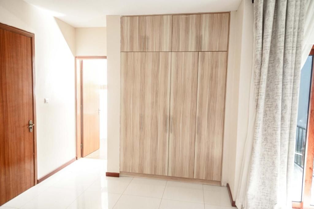 Un couloir avec une armoire en bois, une porte et une fenêtre avec des rideaux.