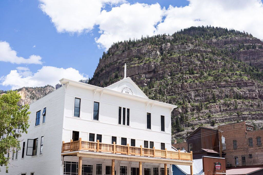 A white building with a balcony, a mountain backdrop, and a sign reading "Western Hotel 1899".
