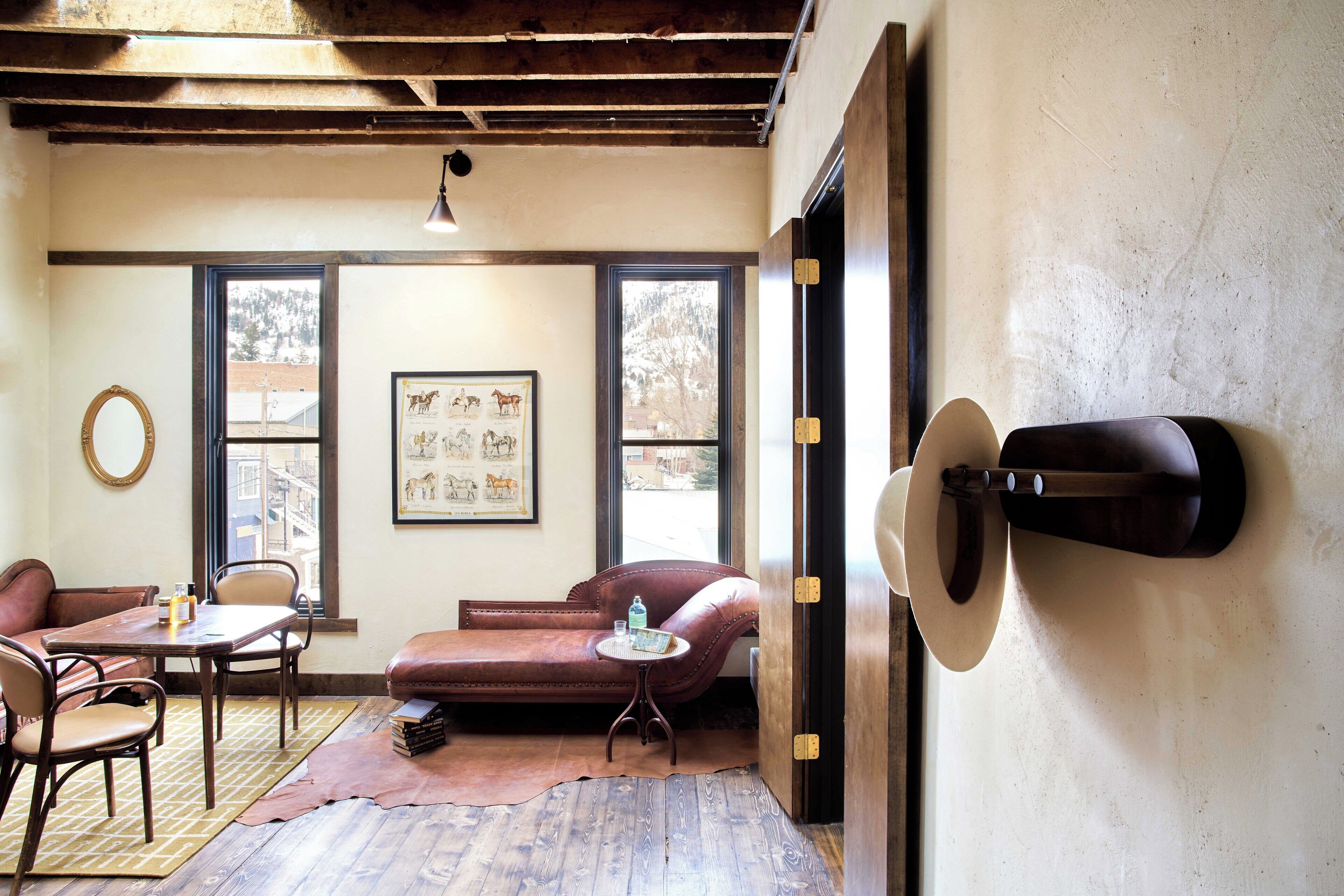 Una habitación acogedora con techo de madera, un sofá de cuero, una mesita y un cuadro en la pared.