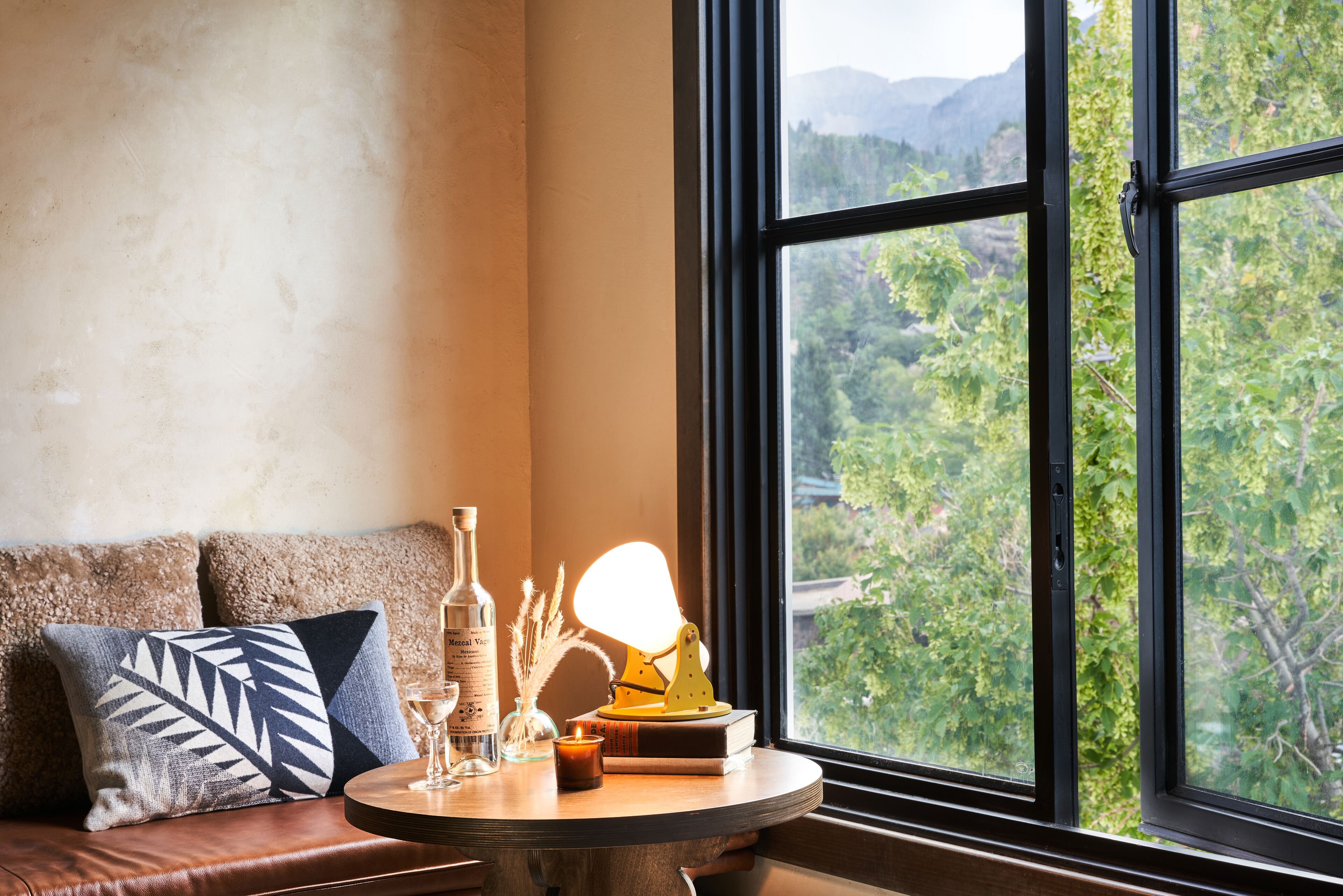 A cozy seating area with a view of a forested landscape through large windows.