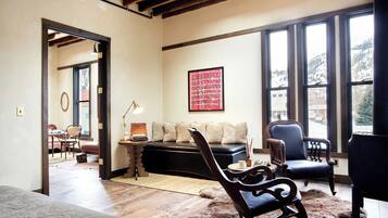 A cozy living room with a fireplace, a sofa, and a dining area visible through an open doorway.