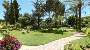 A landscaped garden with a stone pathway, various trees, and a well-maintained lawn. - Renovated studio in Elviria, fantastic sea views (Marbella)