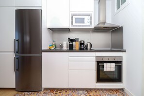 Una cocina moderna con un refrigerador de acero inoxidable, un microondas, una cafetera y un horno pequeño.