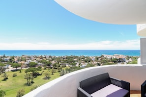 A balcony with a wicker chair, overlooking a coastal town with houses and greenery. - Renovated studio in Elviria, fantastic sea views (Marbella)