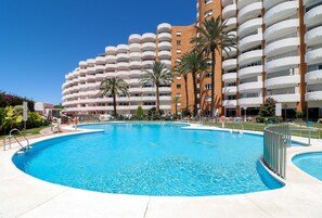 Une grande piscine extérieure entourée d’un hôtel à plusieurs étages doté de balcons.