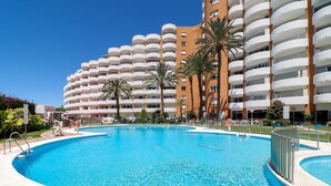 A large outdoor swimming pool surrounded by a multi-story hotel with balconies. - Renovated studio in Elviria, fantastic sea views (Marbella)