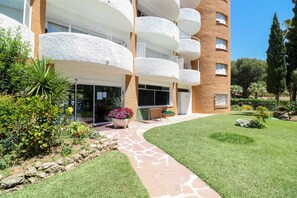 Un edificio moderno con varios balcones, un camino de piedra y jardines bien cuidados.
