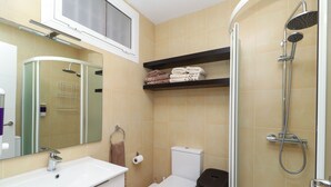 A bathroom with a white sink, a toilet, a shower, and a mirror.