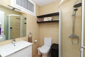 Un baño con un lavabo blanco, inodoro, ducha y espejo.
