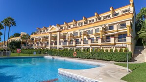 Un hotel con piscina, varios balcones y un jardín bien cuidado.