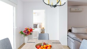 Una camera d'albergo moderna con zona pranzo, divano e lampadario.