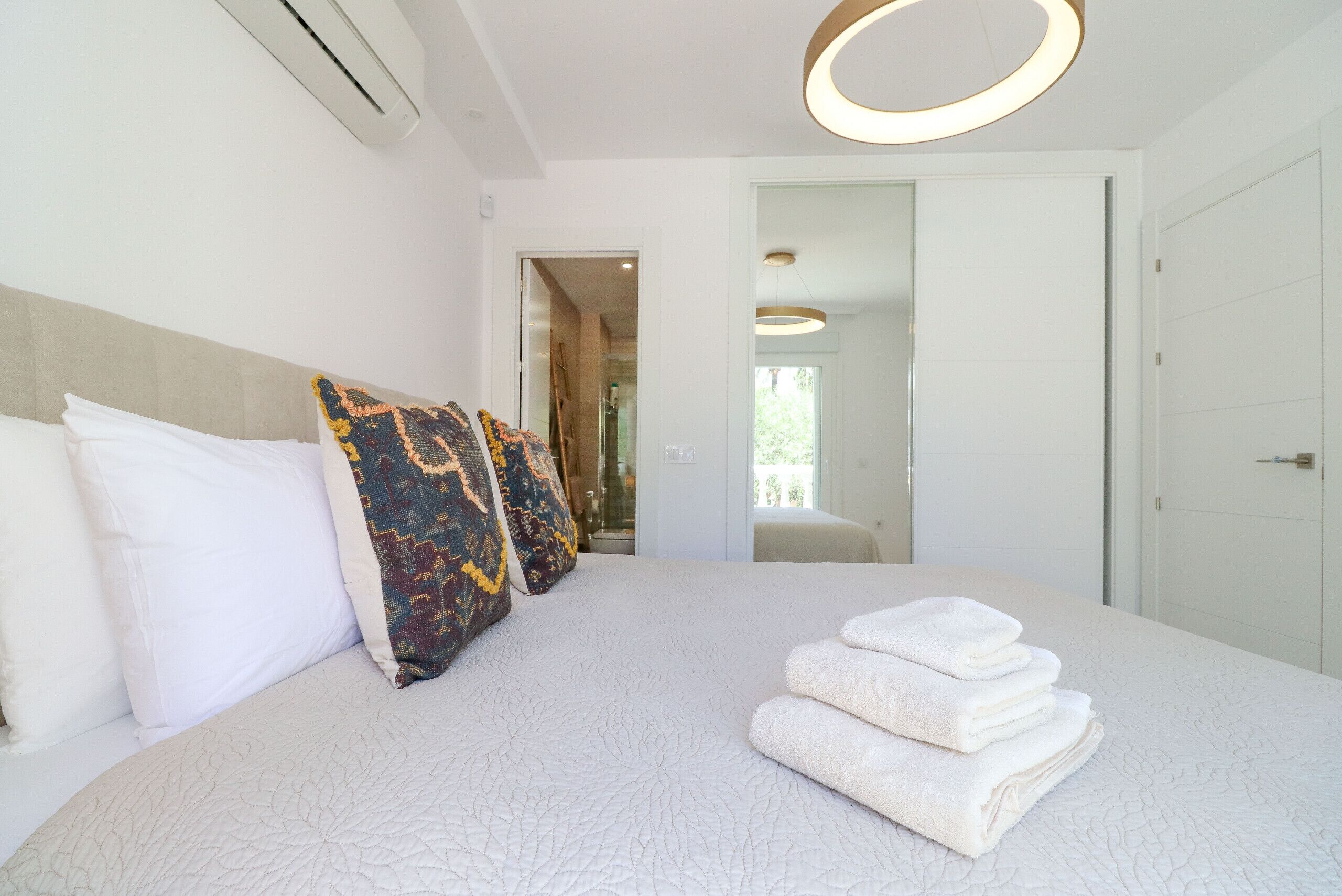 A modern hotel room with a large bed, white bedding, and a neatly folded set of towels.