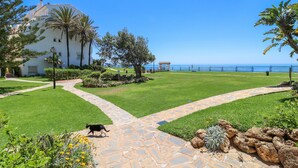 Un giardino curato con un vialetto in pietra che conduce a un edificio con vista sul mare.