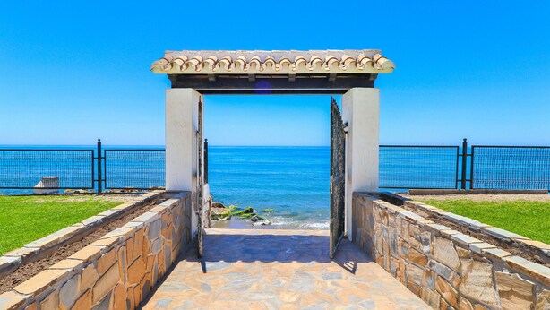 Un vialetto in pietra conduce a una spiaggia, con un pergolato sopra.