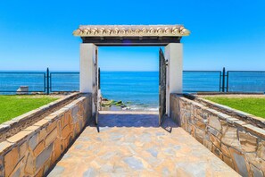 Un sendero de piedra que conduce a una playa, con una pérgola en la parte superior.