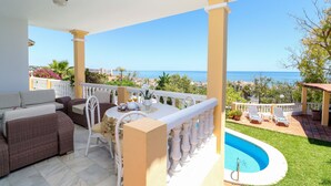 Un balcón con piscina, mobiliario exterior y vistas al mar.