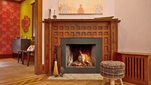 Una habitación con chimenea, alfombra, banca y una pared con motivo decorativo.