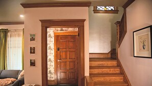 Una escalera de madera con escalones y barandilla, que conduce a una puerta con papel tapiz floral.