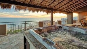 A hot tub with a view of the ocean and a cityscape in the background.