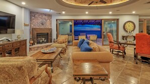 A spacious living room with a fireplace, comfortable seating, a large TV, and a scenic view through the glass doors.