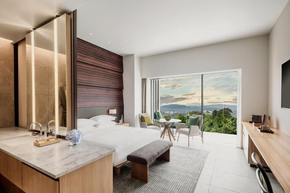 Una habitación de hotel moderna con una cama grande, un escritorio y un balcón con vistas a la ciudad.