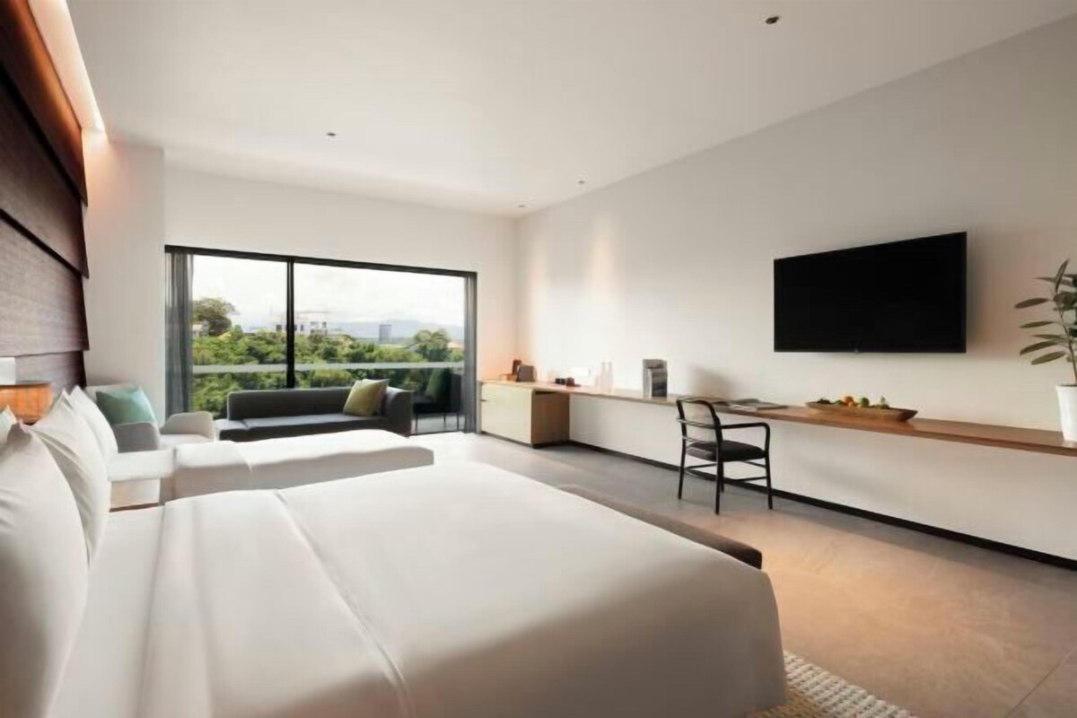 Una habitación de hotel moderna con una cama grande, un escritorio y un televisor montado en la pared.