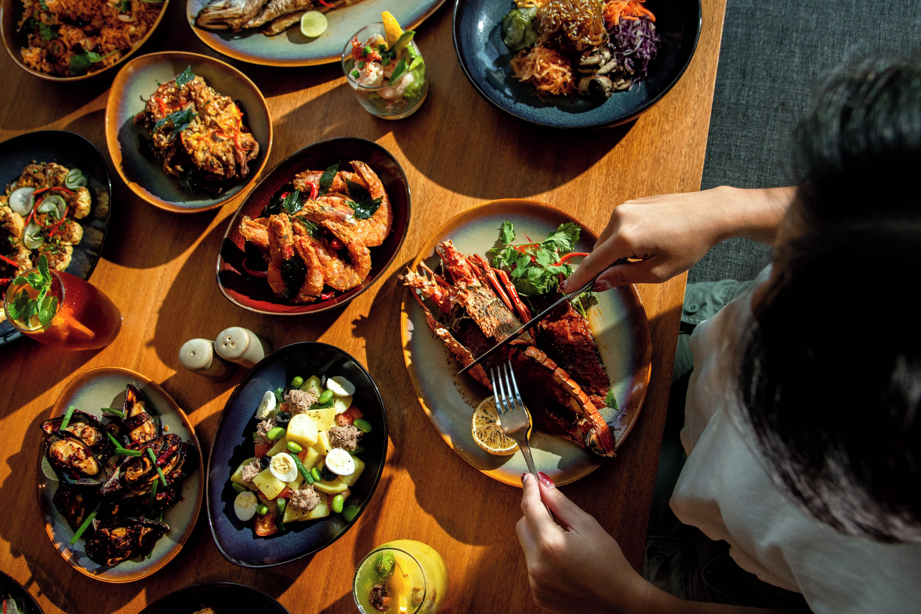 A dining table with various dishes, a person eating, and salt and pepper shakers.