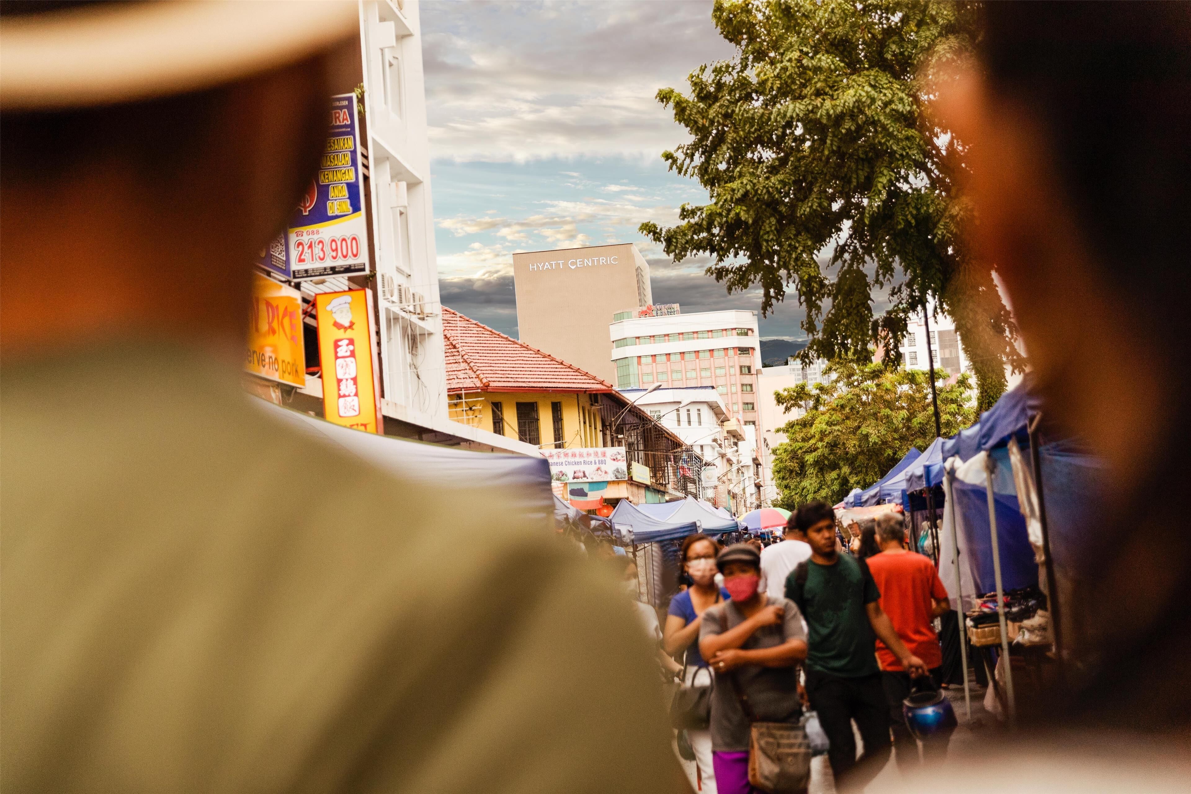 A busy street with market stalls and a prominent hotel named 'HYATT CENTRIC' in the background.
