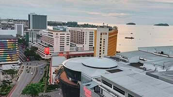 A modern building with a curved facade, a parking lot, and a view of the sea.